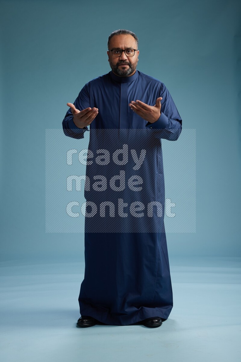 Saudi Man without shimag Standing Interacting with the camera on blue background
