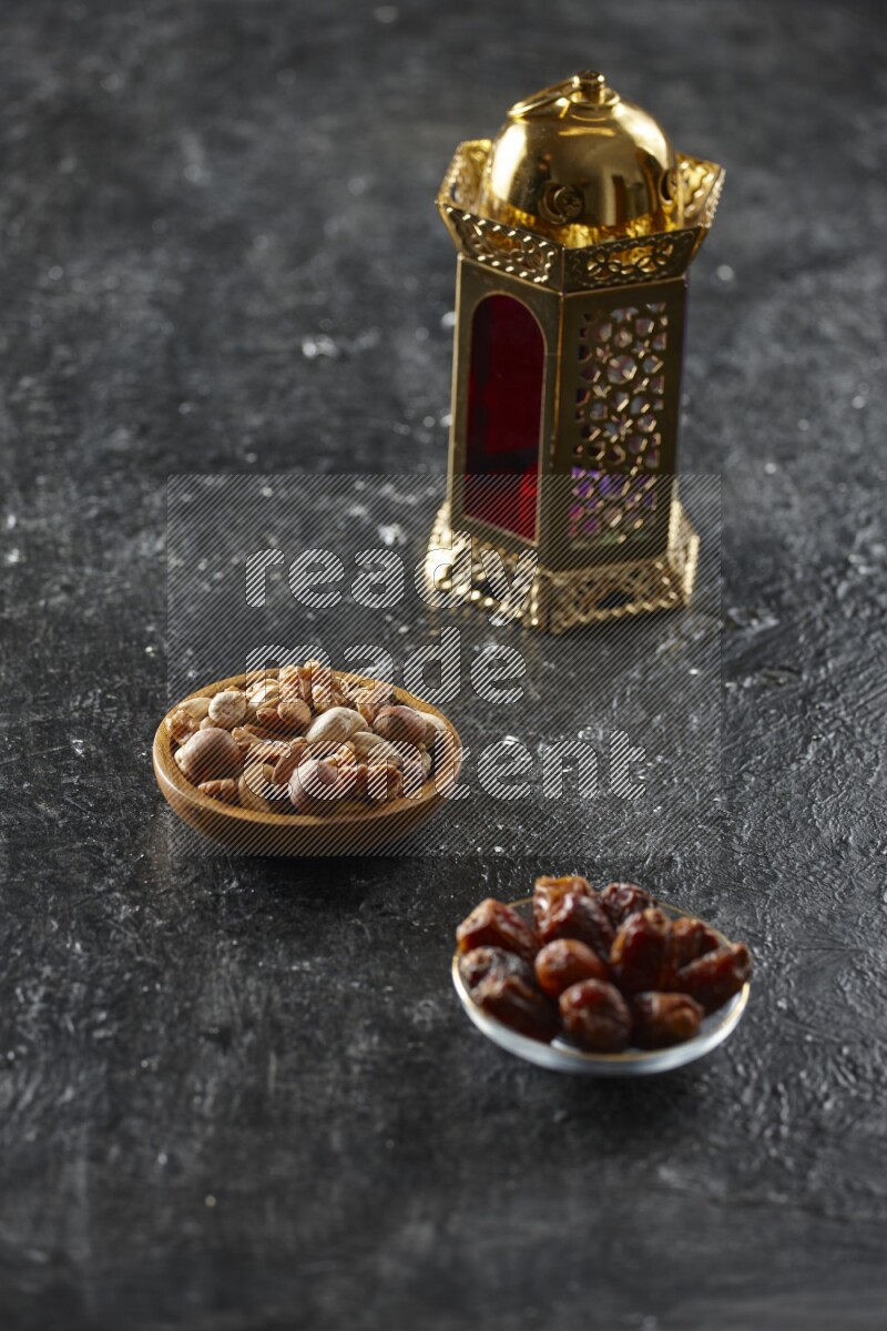 A golden lantern with different drinks, dates, nuts, prayer beads and quran on textured black background
