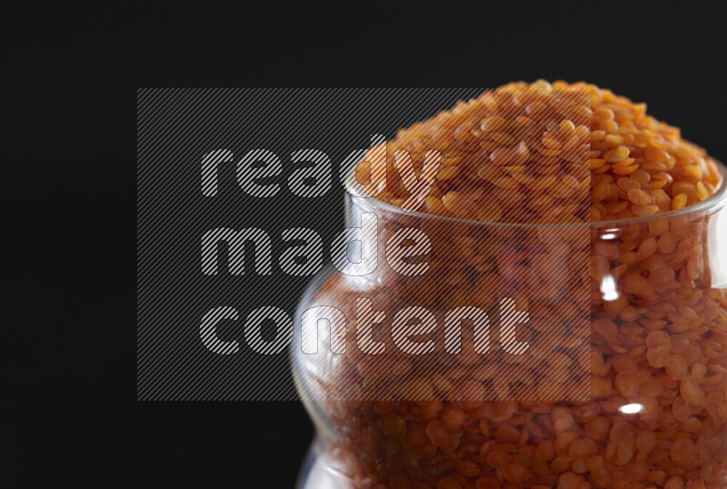 Lentils in a glass jar on black background