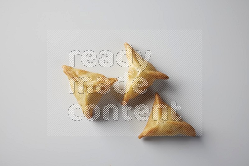 Three fried sambosa from a top angle on a white background