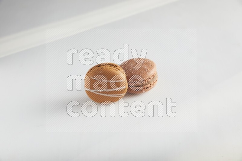 45º Shot of of two assorted Brown Irish Cream, and Brown Hazelnuts macarons on white background