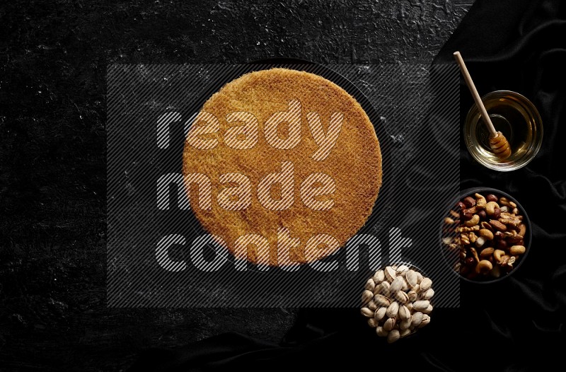 Konafa with nuts and honey in a dark setup