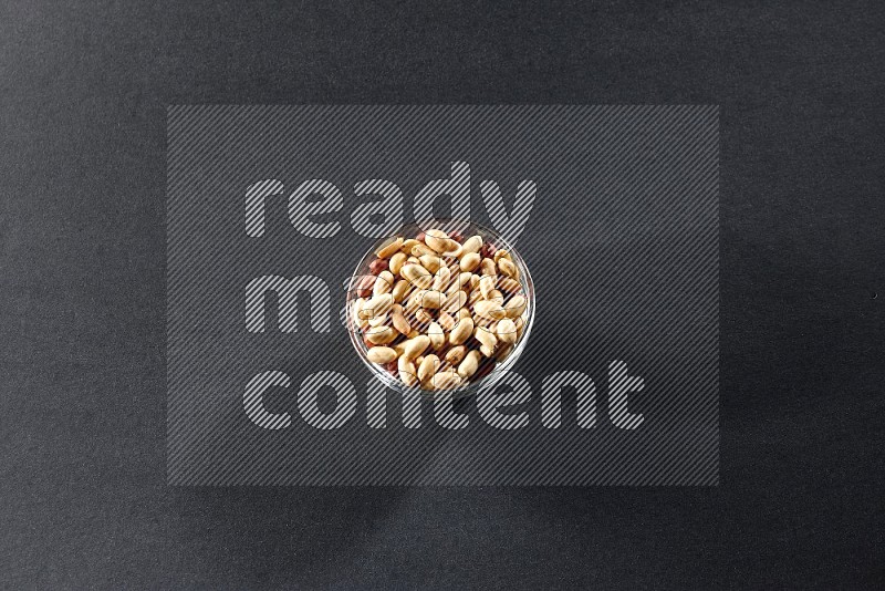 A glass bowl full of peeled peanuts on a black background in different angles