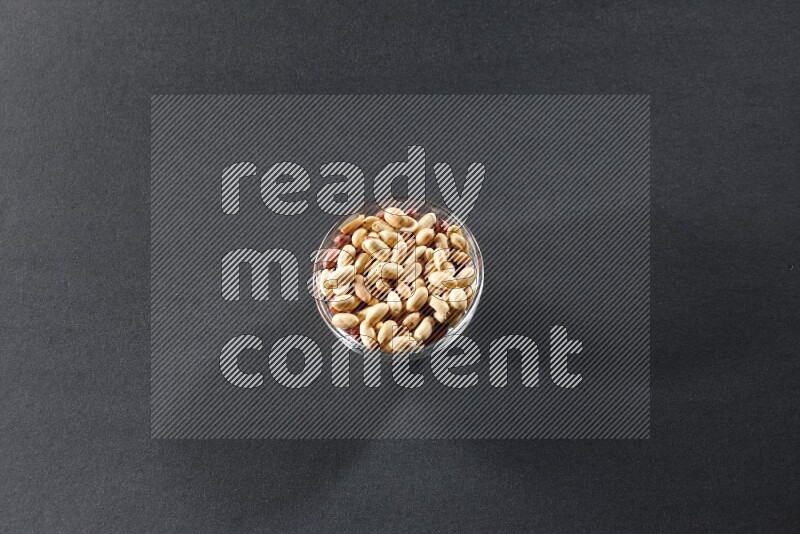 A glass bowl full of peeled peanuts on a black background in different angles