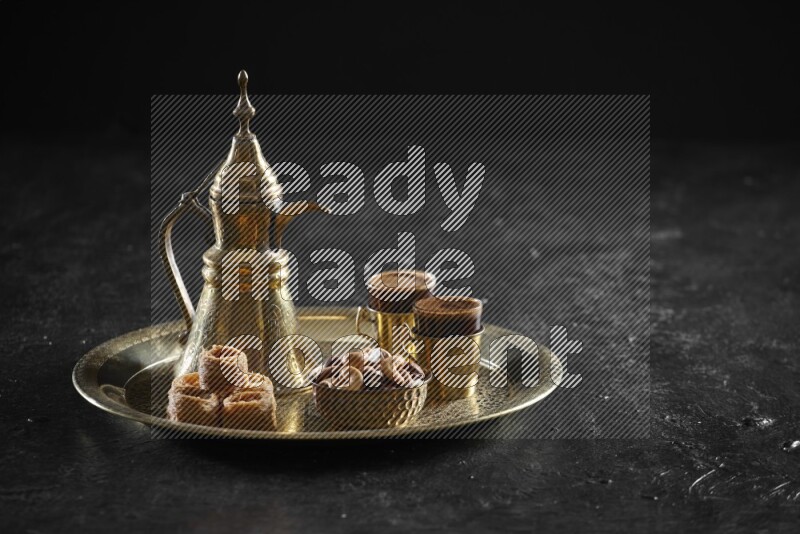 Oriental sweets with nuts and a drink on a metal tray in a dark setup