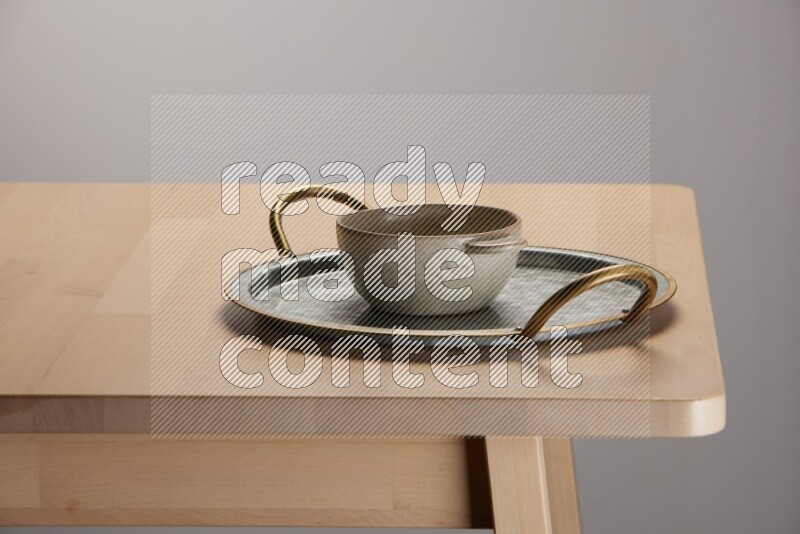 off white bowl placed on a rounded stainless steel tray with golden handels on the edge of wooden table