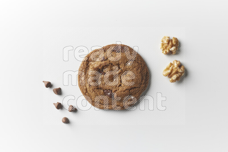 A single chocolate chips cookie with chocolate and walnuts beside it on a white background