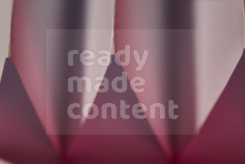 صورة مجردة مقربة تظهر طيات ورقية هندسية حادة بتدرجات اللون الأبيض و الأحمر