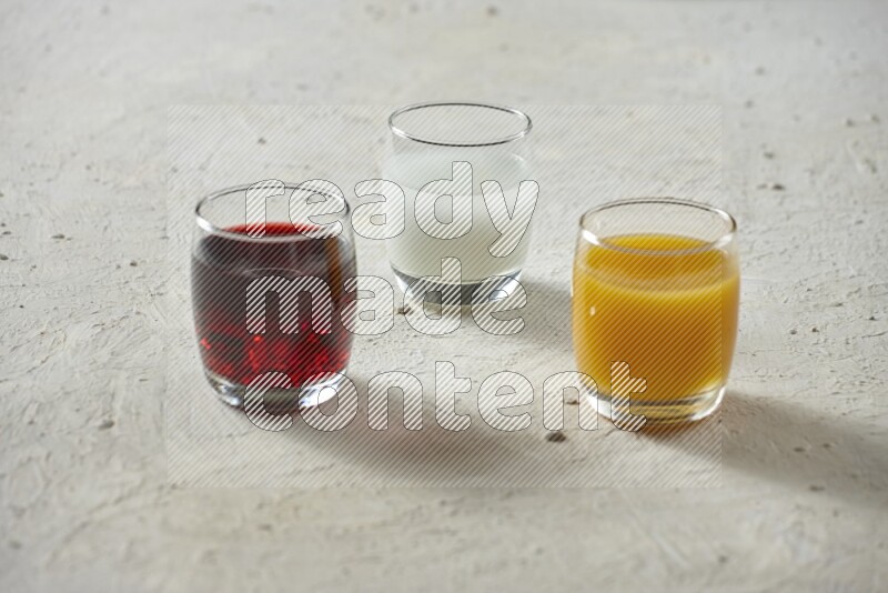Cold drinks in a glass cup such as water, tamarind, qamar eldin, sobia, milk and hibiscus on textured white background
