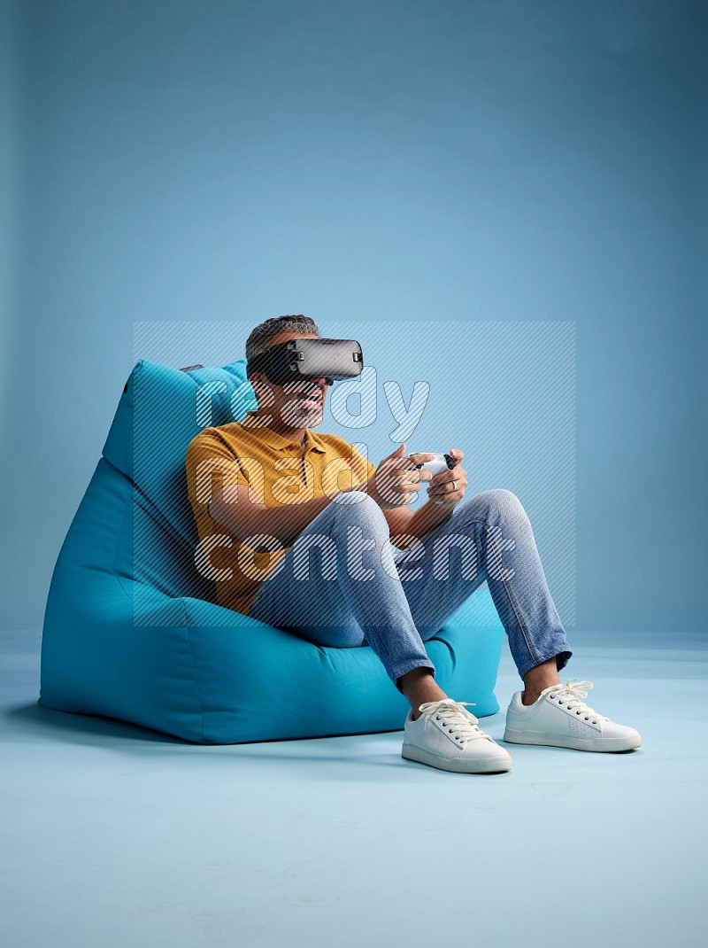 A man sitting on a blue beanbag and gaming with VR