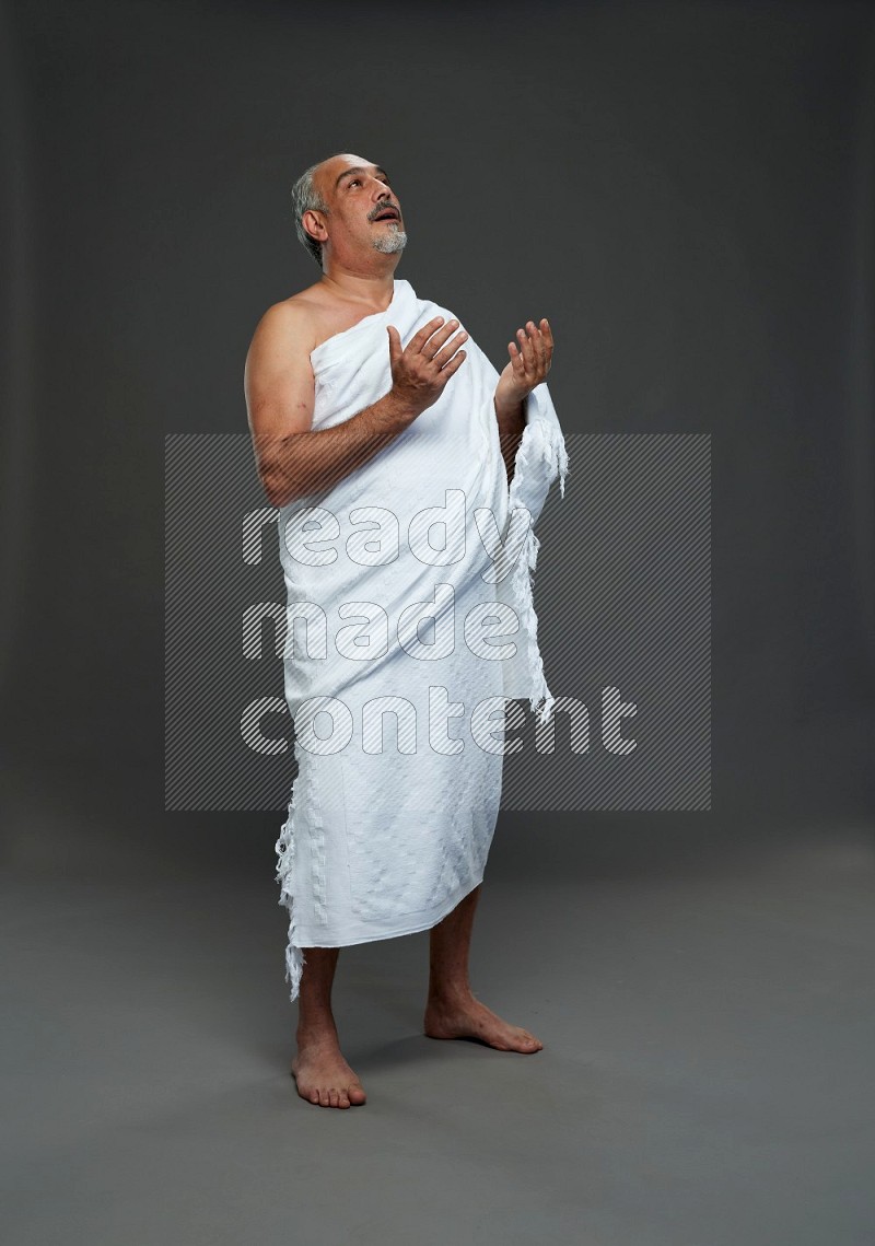 A man wearing Ehram Standing dua'a on gray background