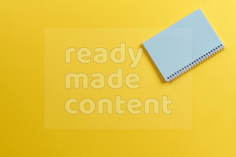 A blue notebook on yellow background (Back to school)