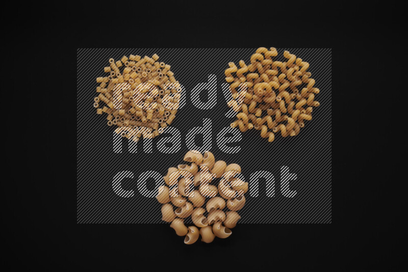 Different pasta types in bunches on black background