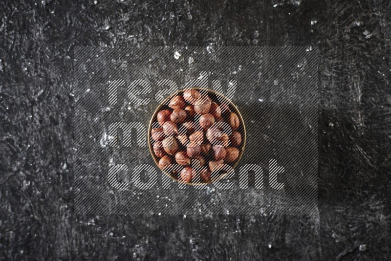 Nuts in a metal bowl in a dark setup