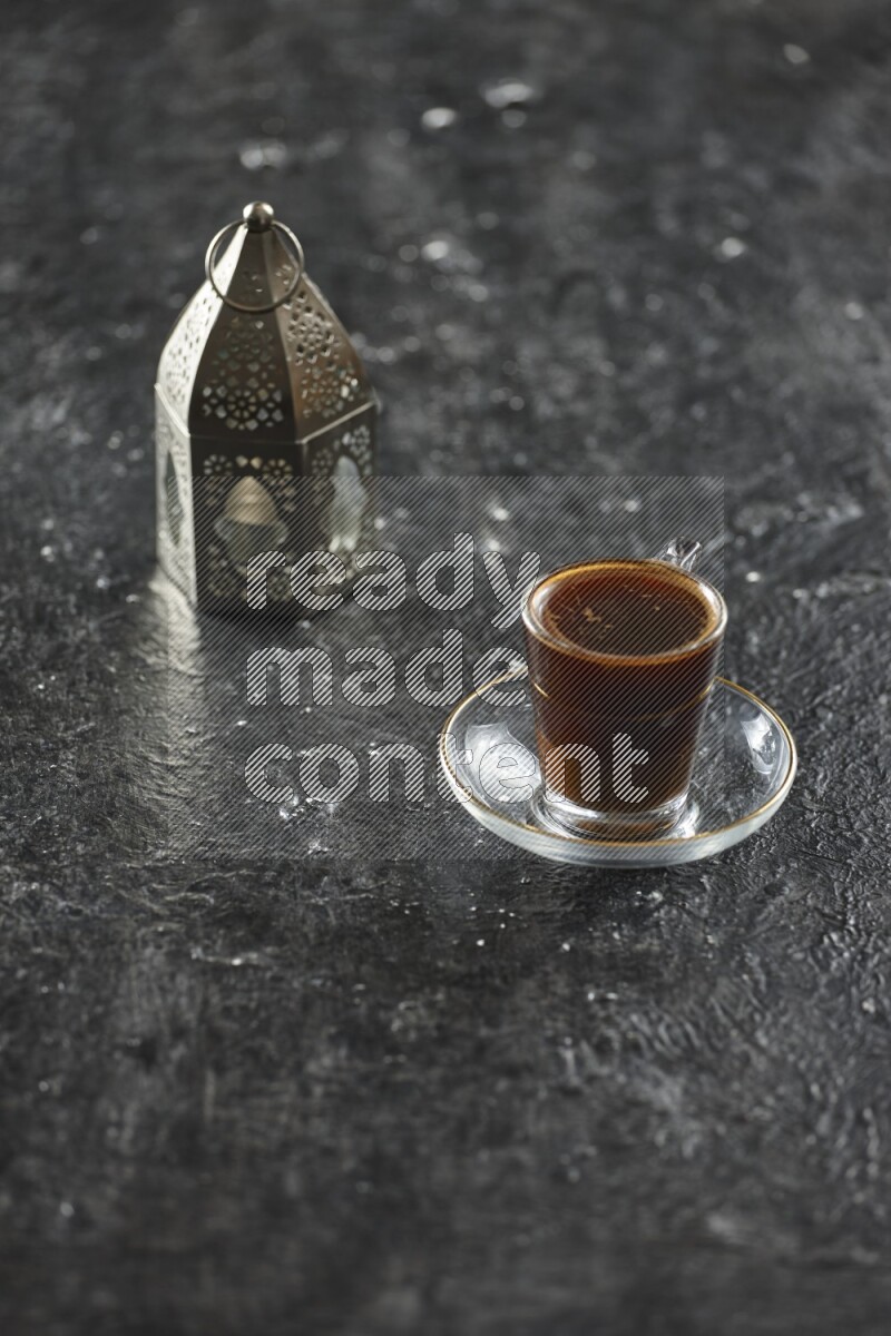 A silver lantern with different drinks, dates, nuts, prayer beads and quran on textured black background