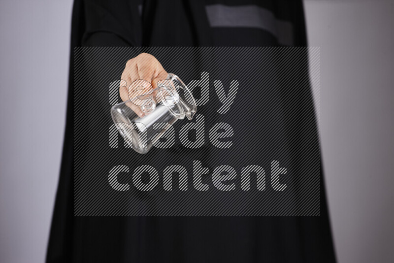 A woman in black abaya holding different glassware in different positions