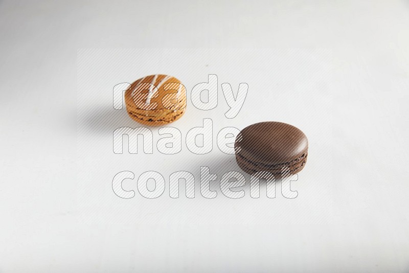 45º Shot of of two assorted Brown Irish Cream, and Brown Dark Chocolate macarons on white background