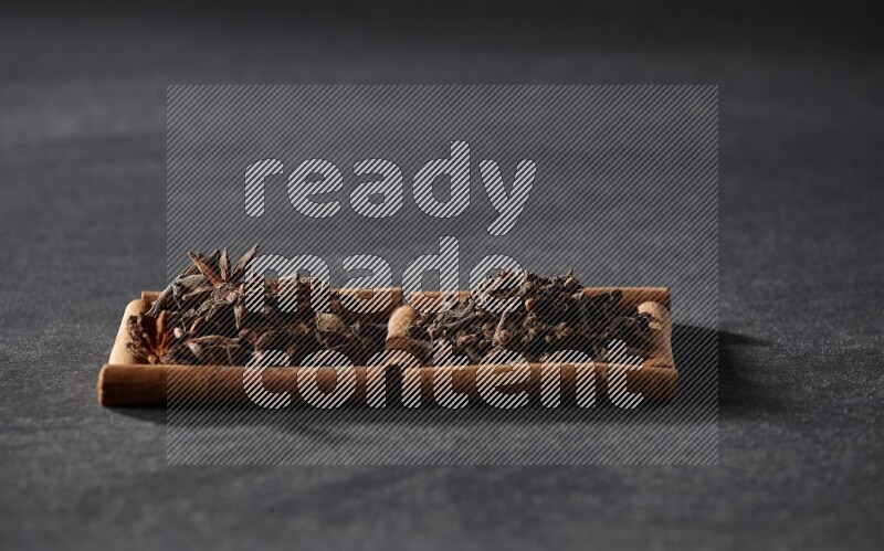 مربعان من أعواد القرفة ممتلئان باليانسون النجمي والقرنفل علي خلفية سوداء