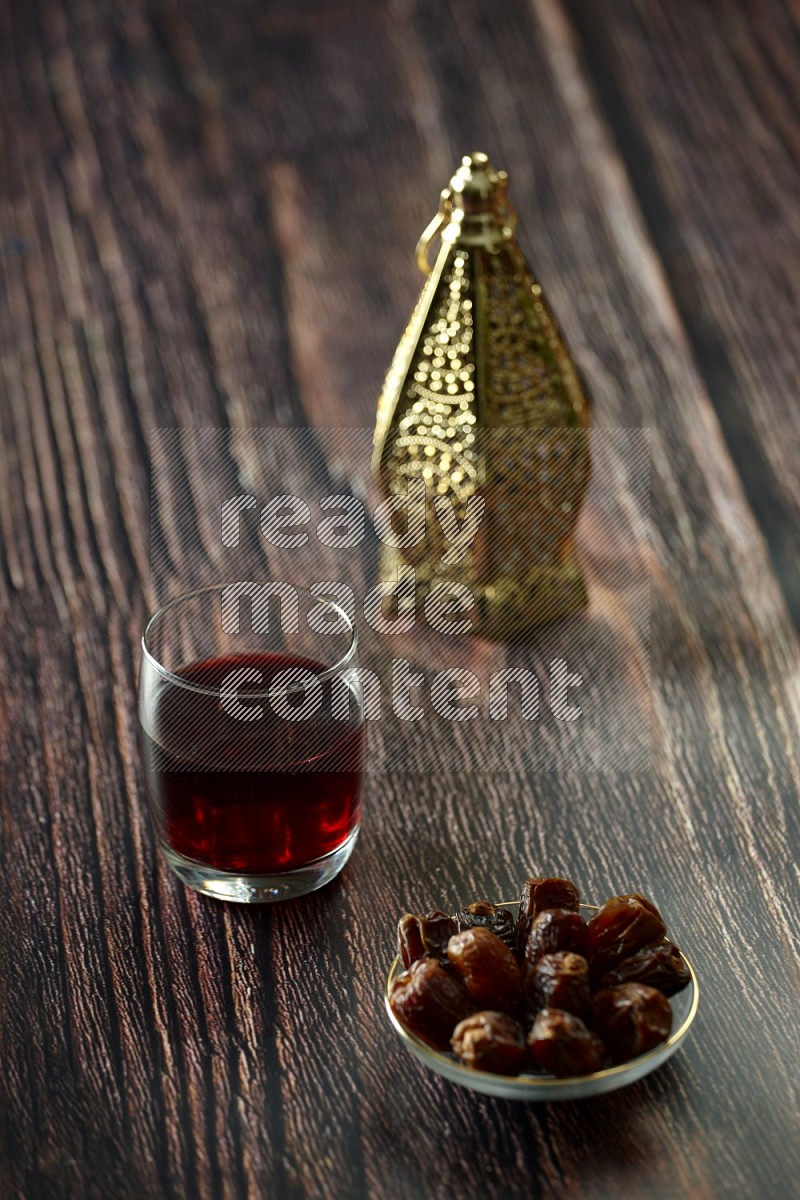 A golden lantern with different drinks, dates, nuts, prayer beads and quran on brown wooden background