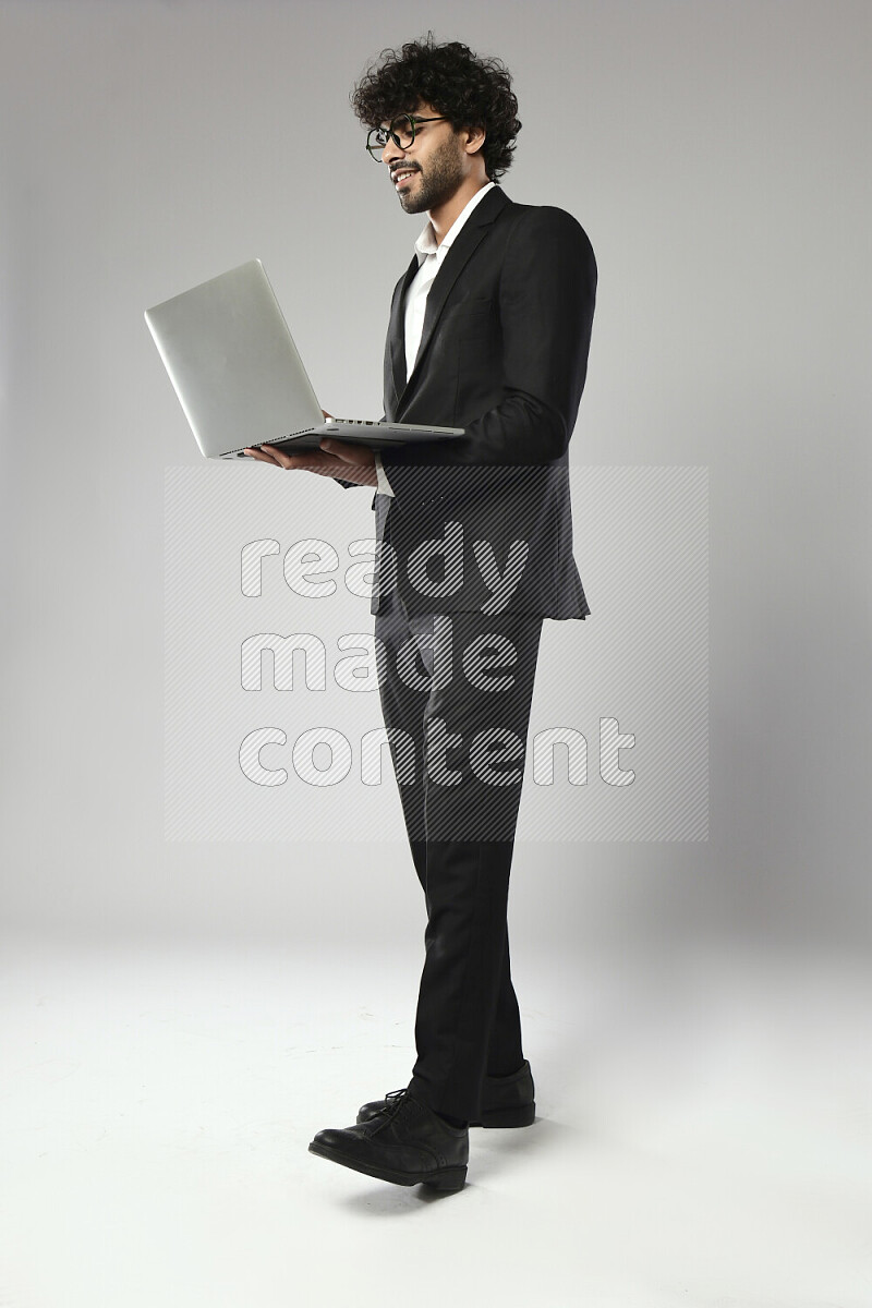 A man wearing formal standing and working on a laptop on white background