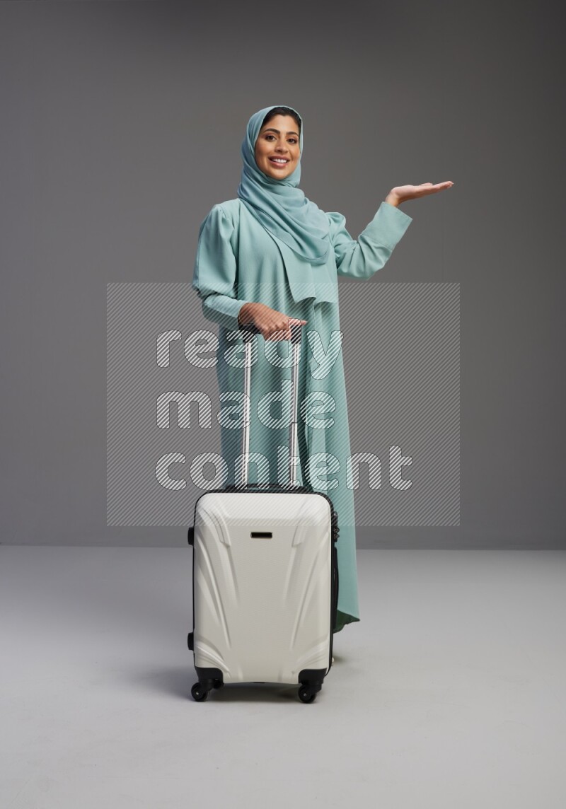 Saudi Woman wearing Abaya standing holding Travel bag on Gray background