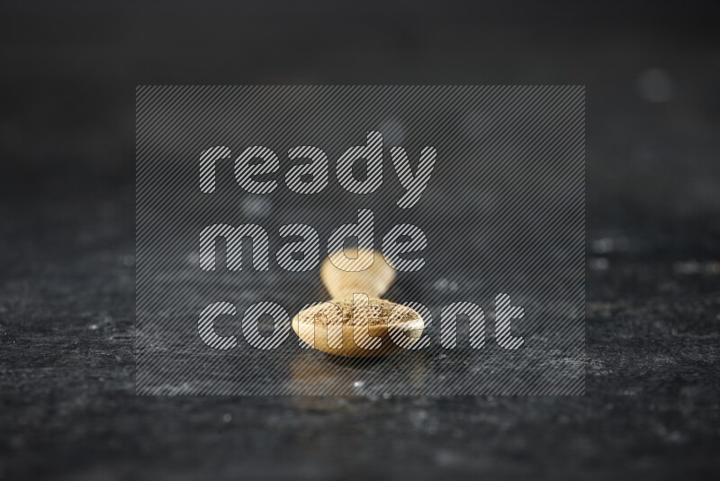 ملعقة خشبية ممتلئة ببودرة الكمون على خلفية سوداء