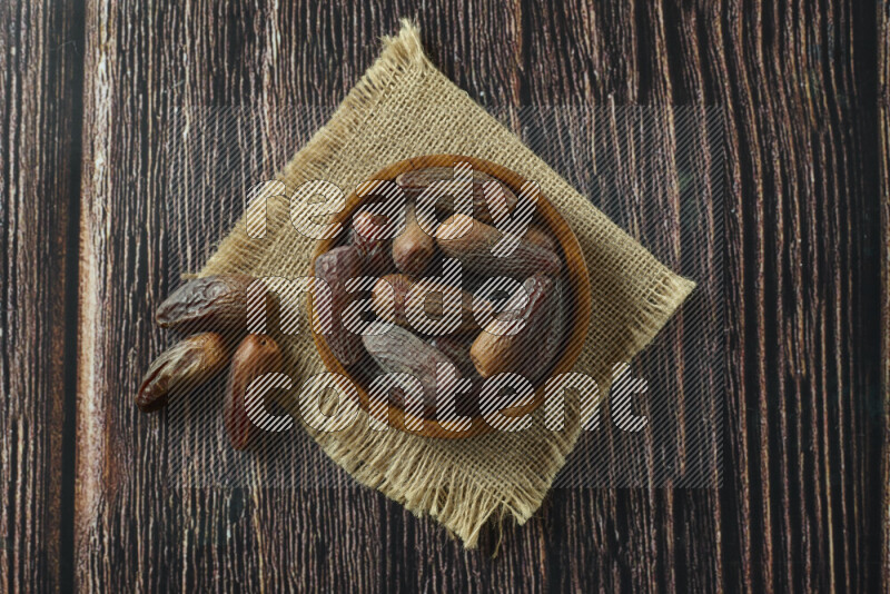 Dates in different bowls (wooden, pottery and glass) on wooden background