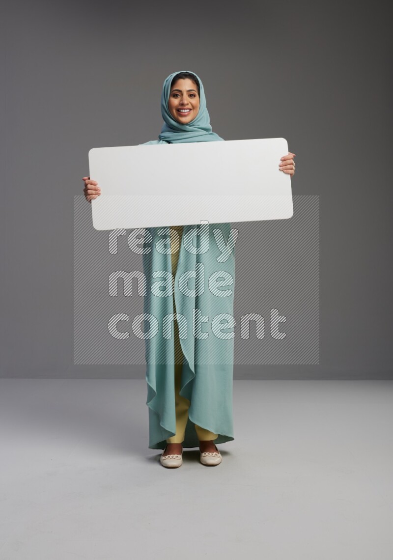 Saudi Woman wearing Abaya standing holding board on Gray background