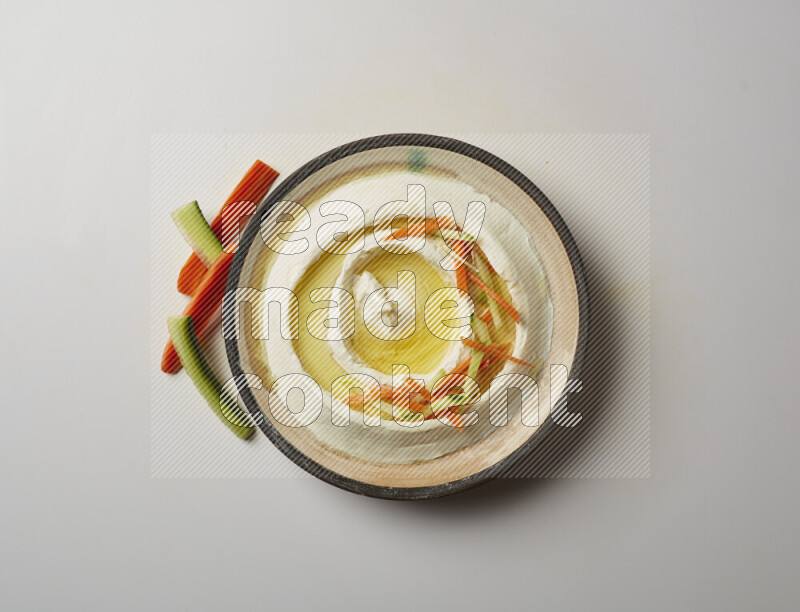 Lebnah garnished with sliced carrots &cucumber in a pottery plate on a white background