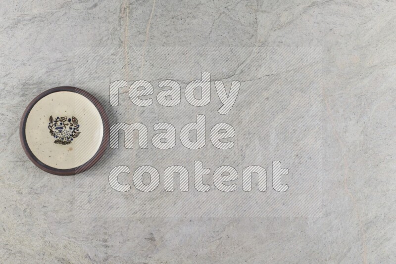 A decorative pottery plate on grey marble background