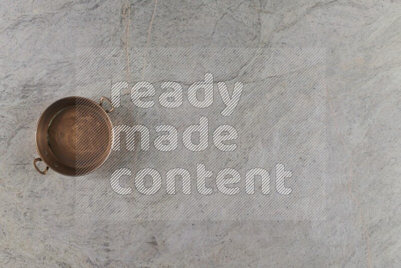 مقلاة نحاسية صغيرة على خلفية من الرخام الرمادي