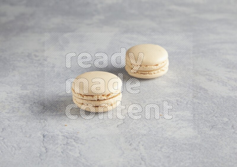 45º Shot of two white marbleCaramel fleur de sel macarons  on white  marble background