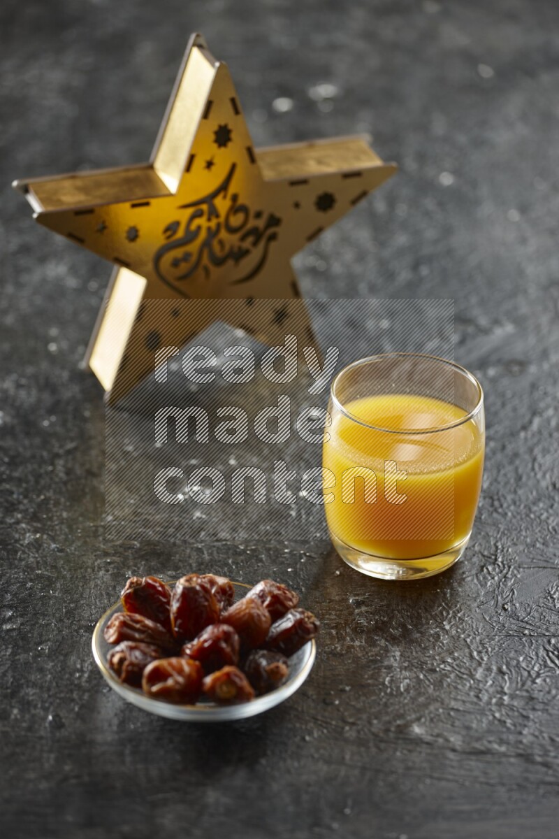 A wooden golden star lantern with different drinks, dates, nuts, prayer beads and quran on textured black background
