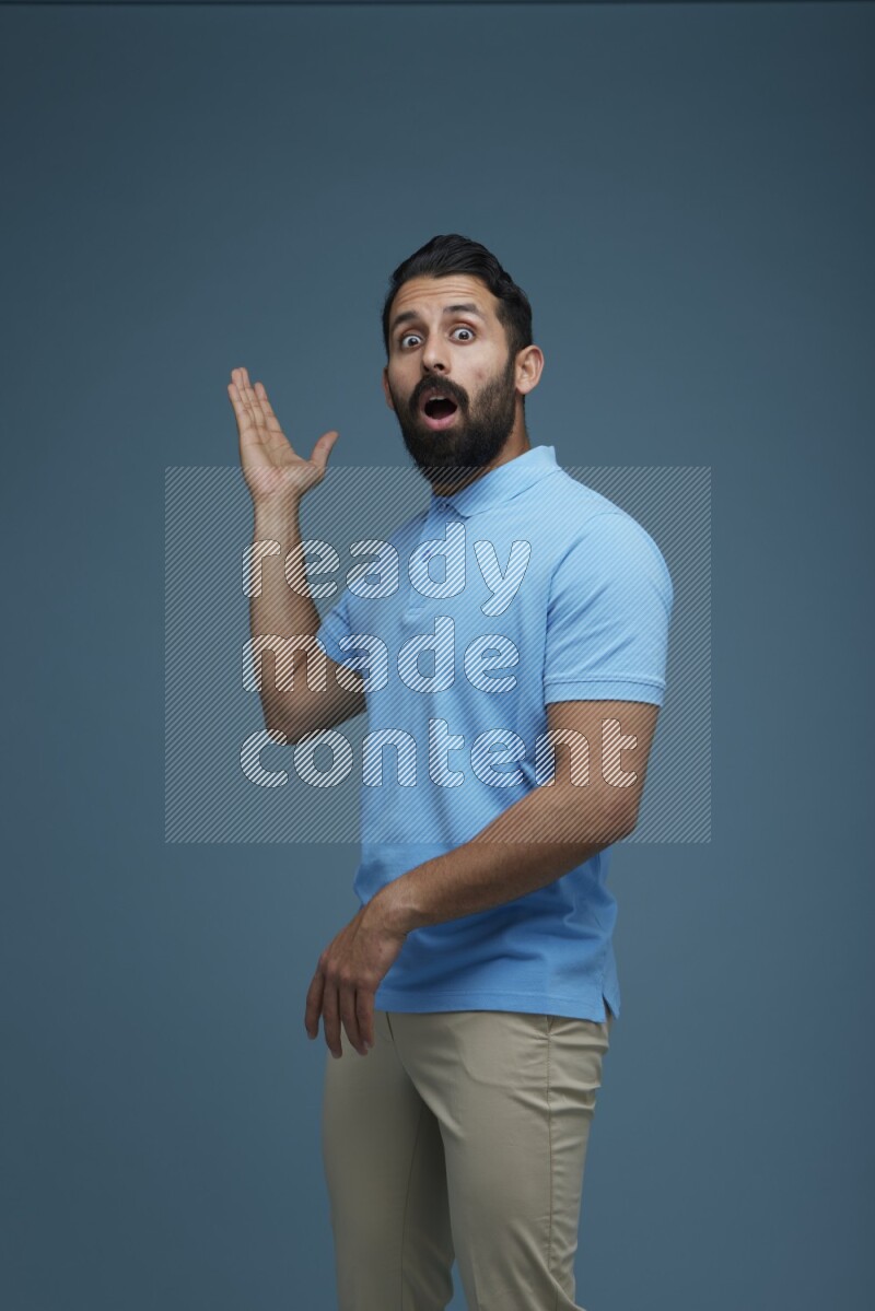 A man pointing  in a blue background wearing a Blue shirt