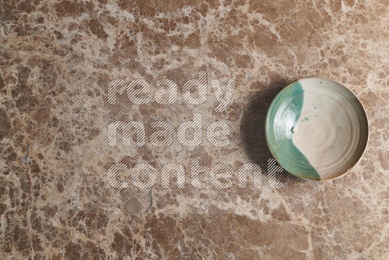 A decorative pottery plate on beige marble background