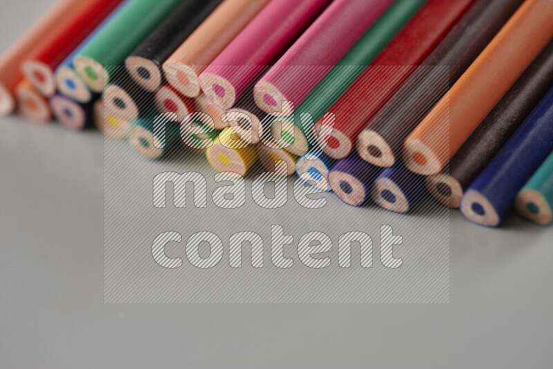 An array of colored pencils on grey background