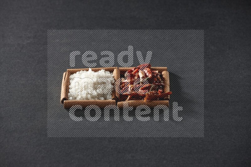 مربعان من أعواد القرفة ممتلئان بالفلفل الحار المجفف والملح الأبيض علي خلفية سوداء