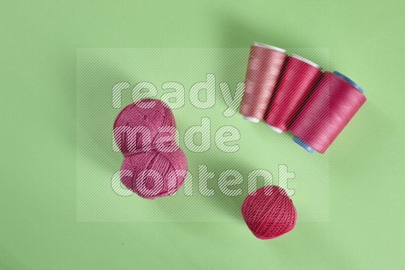 A pink collection of sewing and tailoring tools arranged on a green background