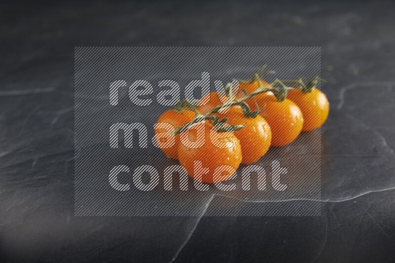 Orange cherry tomato vein on a textured black slate background 45 degree