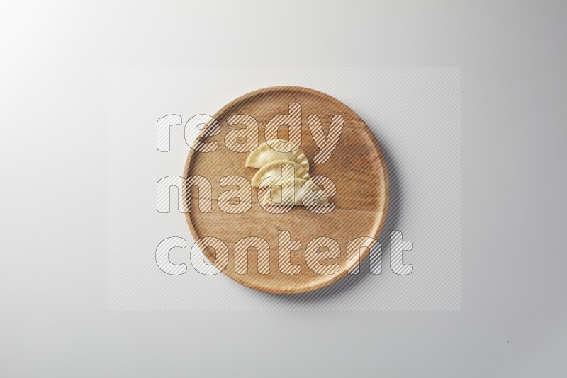 Three Sambosas on a wooden round plate on a white background