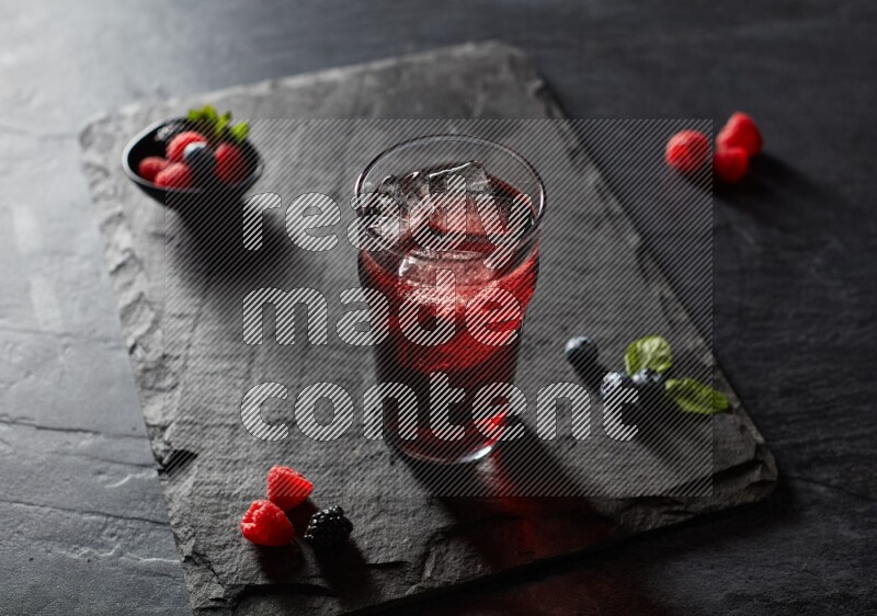 A glass of mixed berries juice on black background