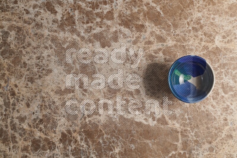 A multicolored pottery bowl on beige marble background