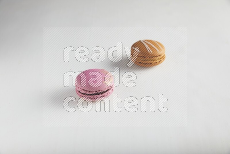 45º Shot of of two assorted Brown Irish Cream, and Purple Strawberry macarons on white background