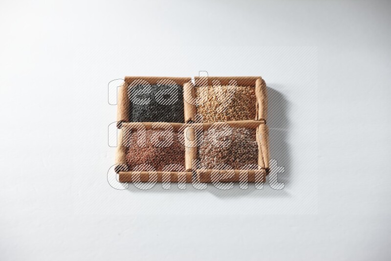 4 مربعات من أعواد القرفة ممتلئة بحبة البركة وبذور الخردل وبذور الكتان وحب الرشاد على أرضية بيضاء