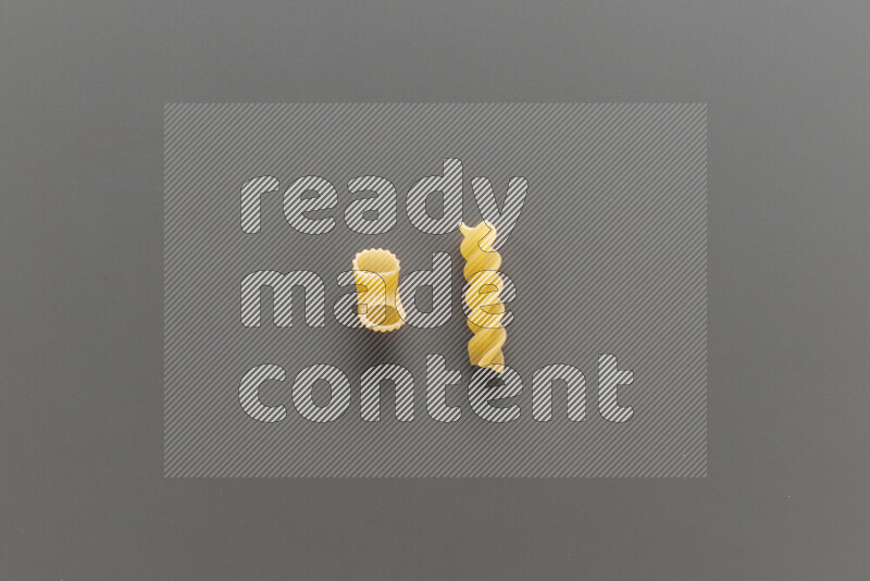 Elbow pasta with other types of pasta on grey background
