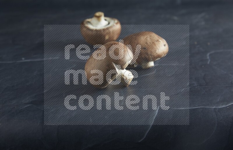 45 degre cremini  mushrooms on a textured black slate background