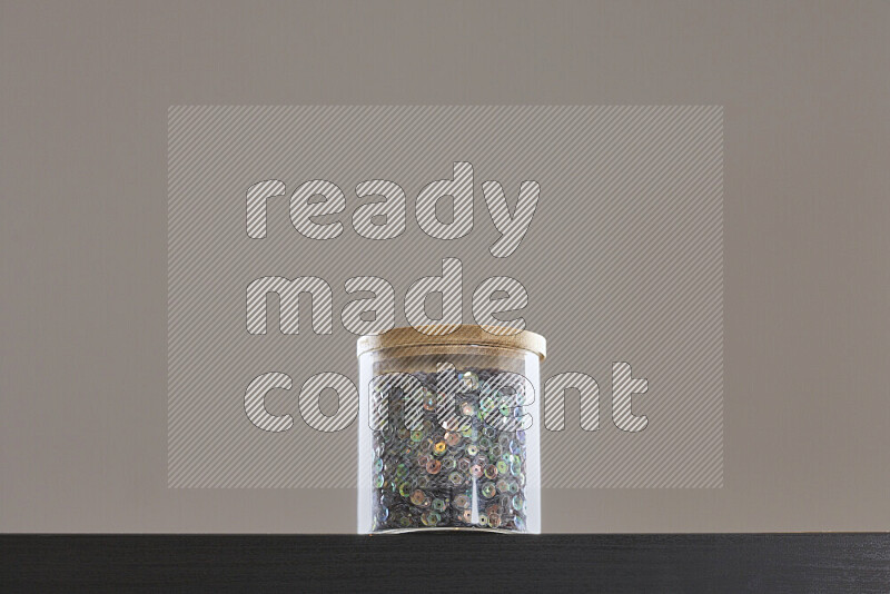 Sequins in a glass jar on black background