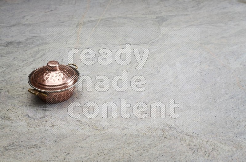 A Small Copper Pot On Grey Marble Flooring