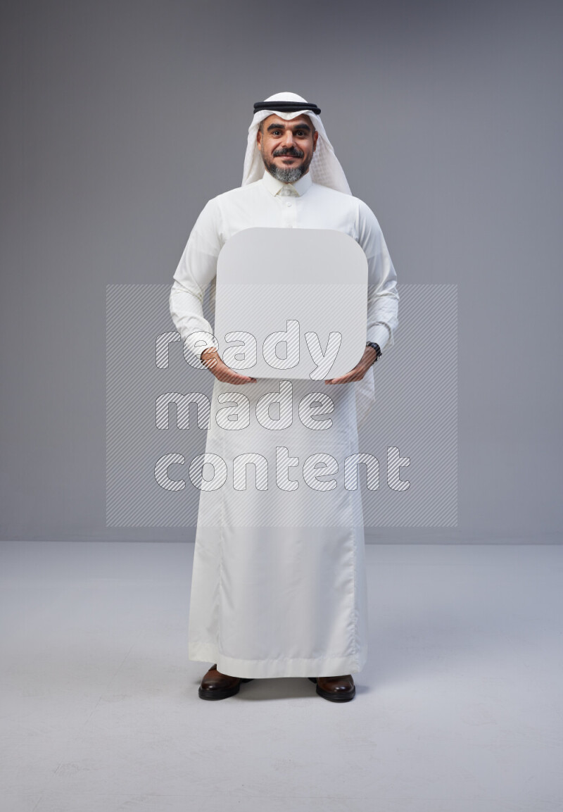 Saudi man Wearing Thob and white Shomag standing holding social media sign on Gray background