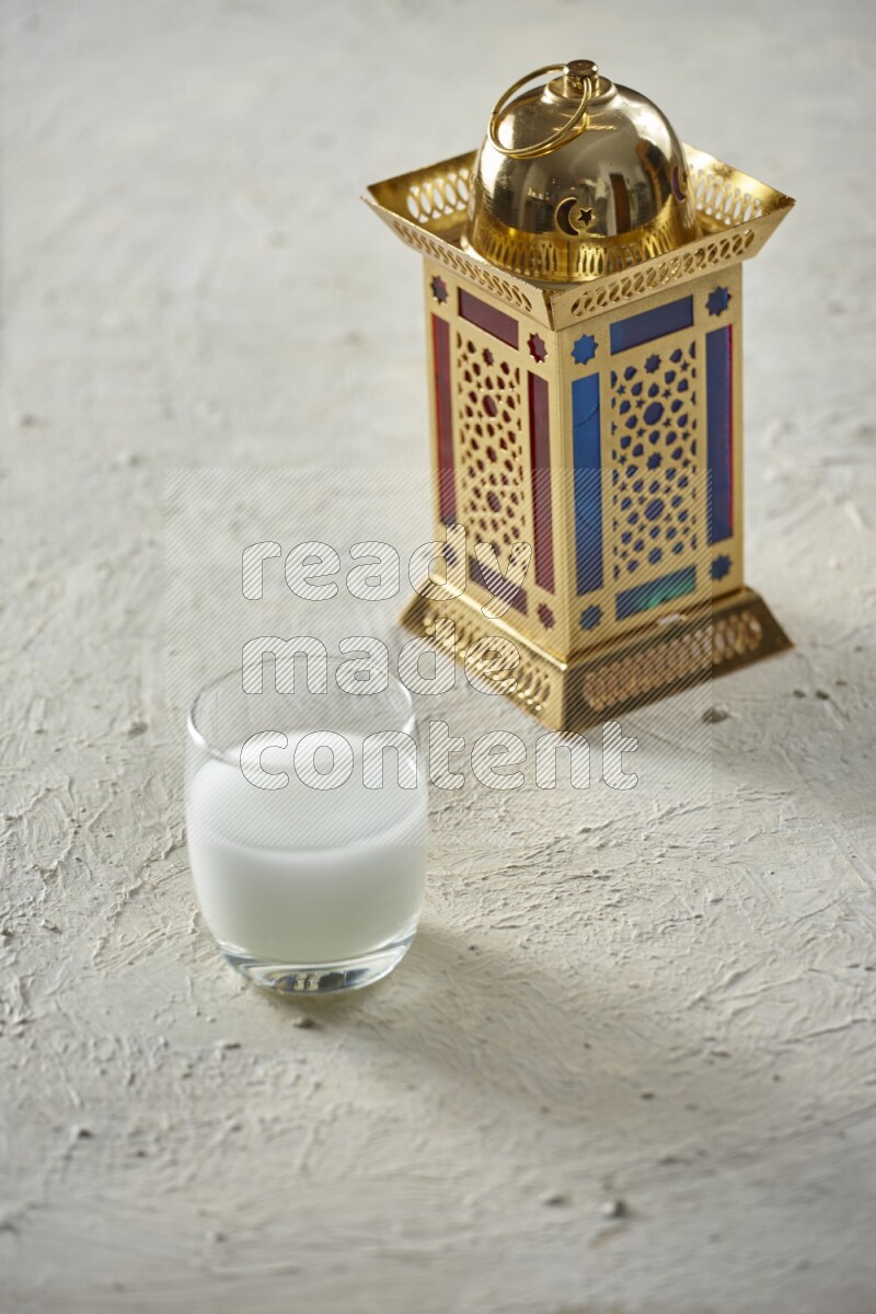 A golden lantern with different drinks, dates, nuts, prayer beads and quran on textured white background